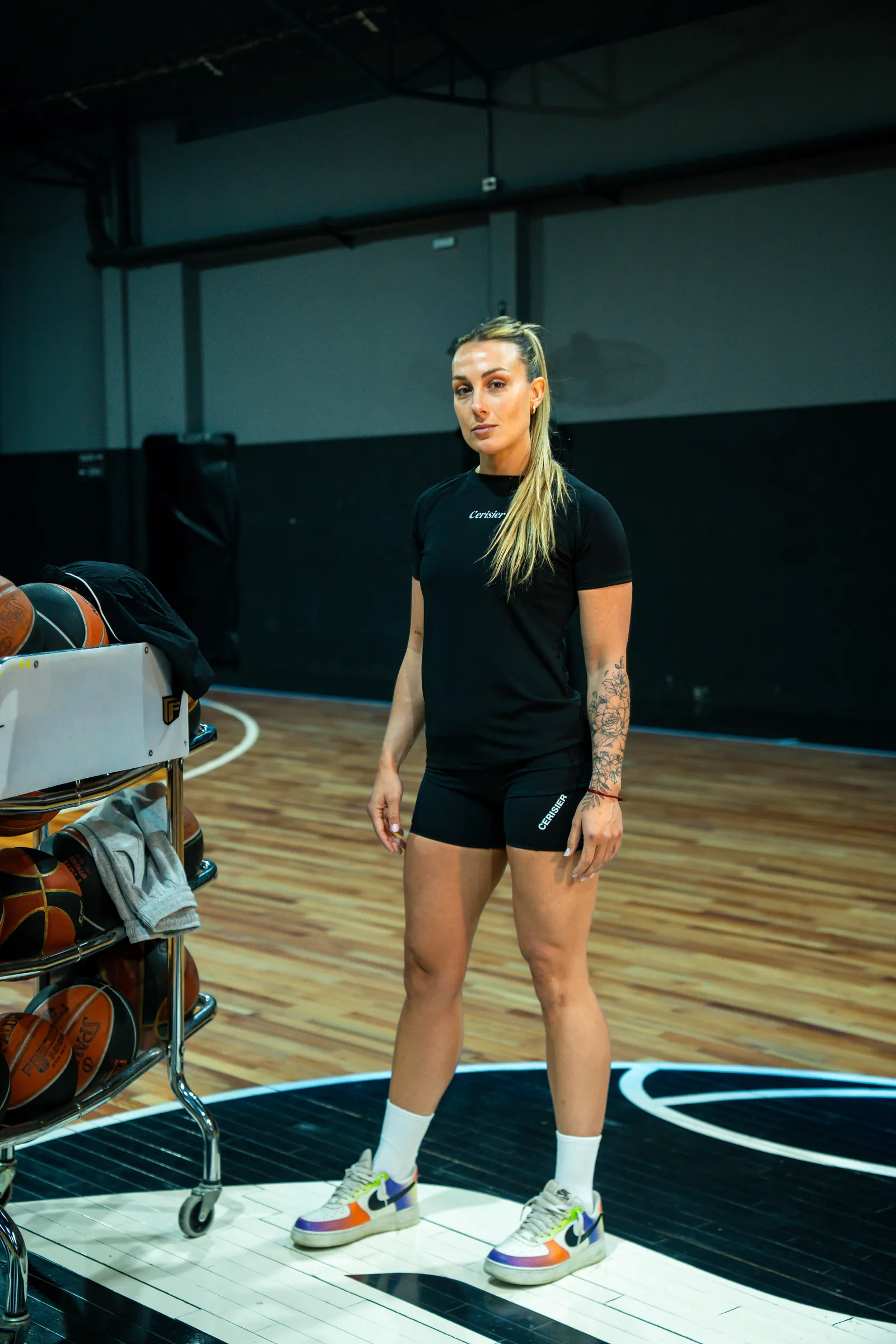 Jugadora de pie en una cancha, con remera y short negros